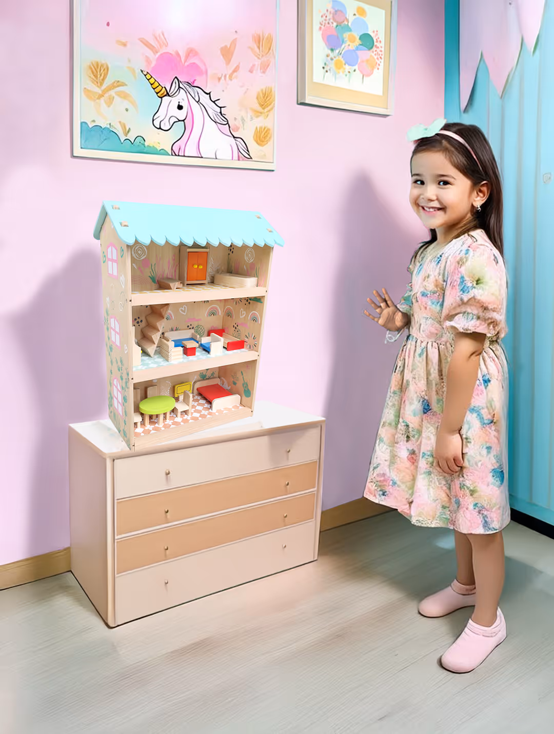 Smiling young girl in a floral dress stands next to a pastel-colored dollhouse on a dresser in a pink-themed room with unicorn artwork.