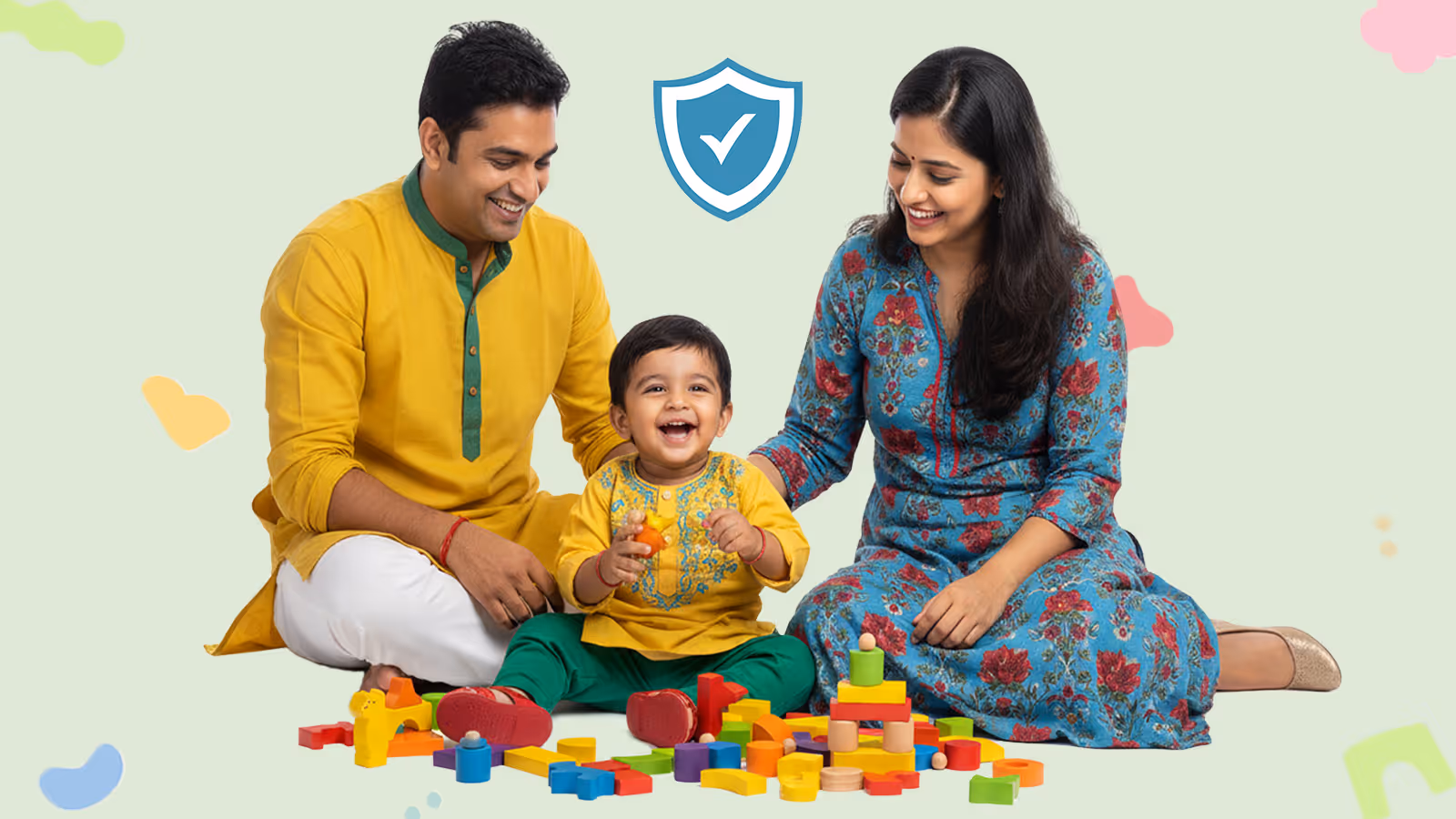 Smiling Indian parents sitting on the floor playing with colorful wooden blocks with their happy toddler.